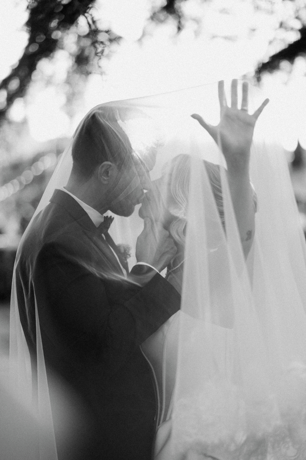 Novios besándose bajo el velo en blanco y negro
